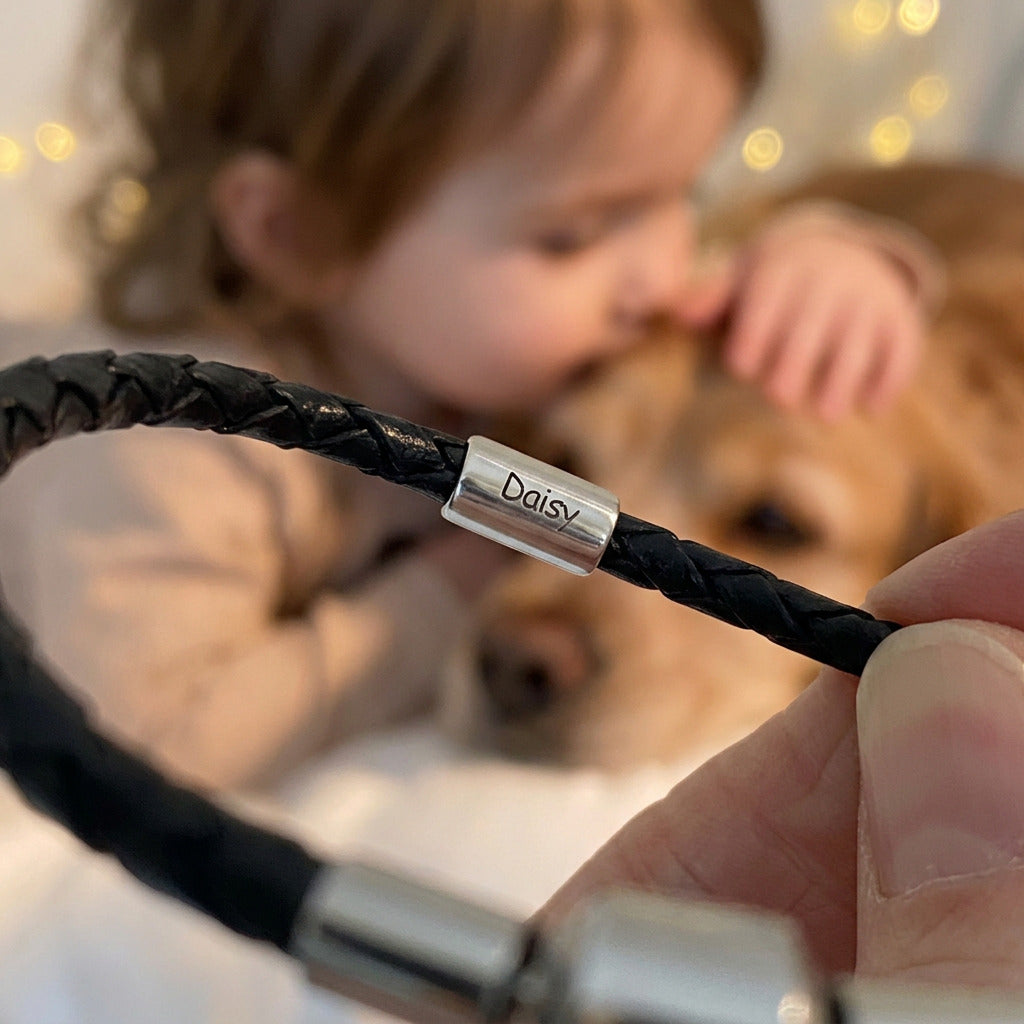 silver bead with an engraved name on a black leather bracelet with a child and a dog in the background
