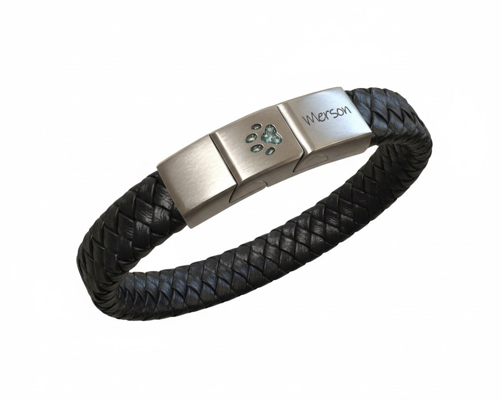 Memorial ashes captured in a pawprint on a braided black leather bracelet