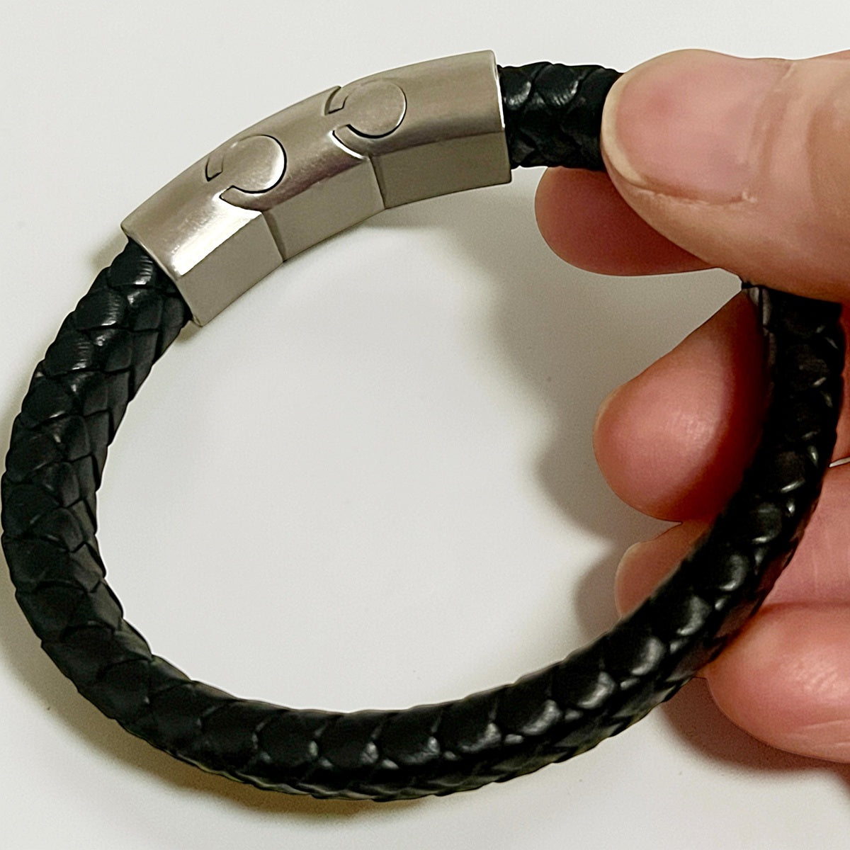 Memorial ashes captured in a pawprint on a braided black leather bracelet