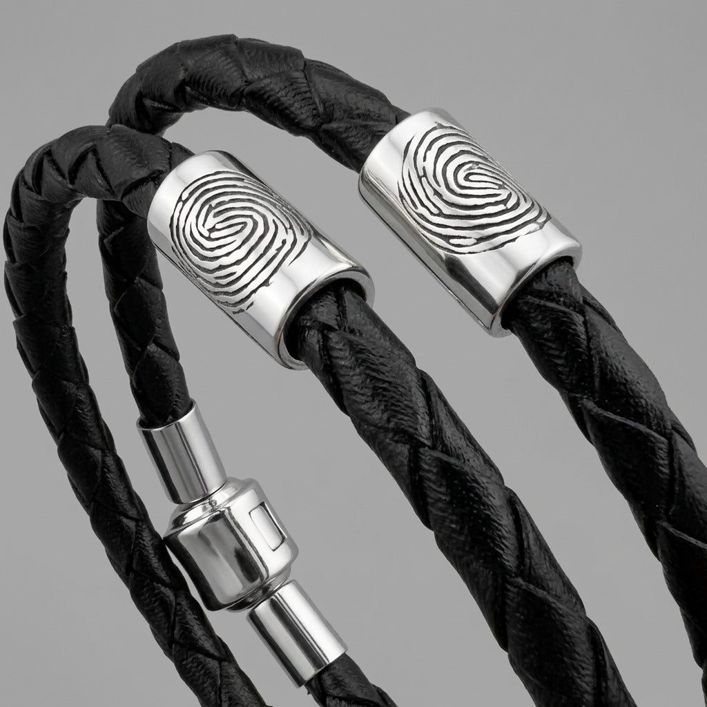 Black braided leather bracelet with silver fingerprint accent caps and a matching silver magnetic clasp.