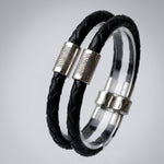 Black braided leather bracelet with silver fingerprint accent caps and a matching silver magnetic clasp, shown close-up with a finger holding it.